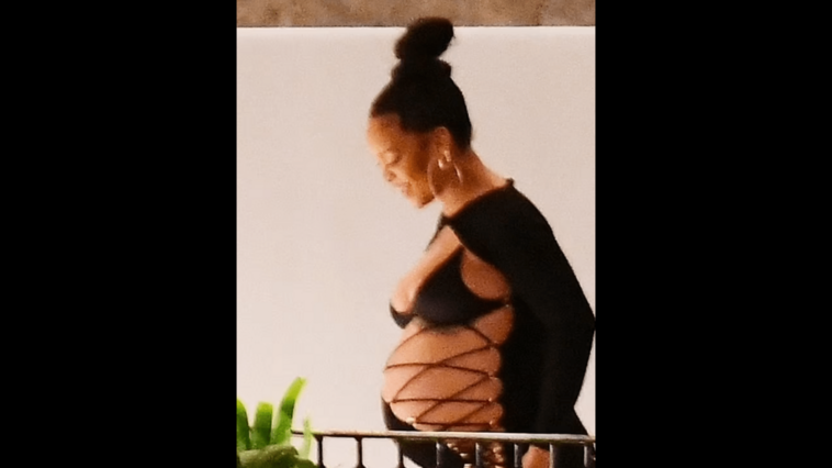 Rihanna proudly shows off her growing belly in a slit dress