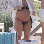 Cosas calientes: la embarazada Lottie Tomlinson exhibió su creciente panza en un diminuto bikini negro mientras descansaba junto a la piscina con su novio Lewis Burton en Ibiza el domingo.