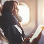 Two females going on business trip by plane. A woman reading an e-book on a smartphone.