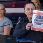 Albuquerque Police Deputy Chief of Investigations Cecily Barker holds a flyer with photos of a car wanted in connection with Muslim men murdered as Governor Michelle Lujan Grisham looks on in Albuquerque, New Mexico, Sunday, Aug. 7, 2022. Authorities investigating the killings of four Muslim men said they are looking for help finding a vehicle believed to be connected to the deaths in New Mexico's largest city. A Muslim man was killed Friday, Aug. 5, 2022, in Albuquerque, and ambush shootings killed three other Muslim men over the past nine months. (Adolphe Pierre-Louis/Albuquerque Journal via AP)