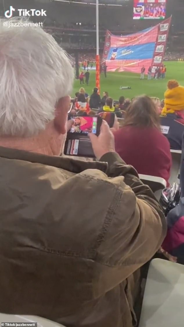 ¡Ciertamente es un fan!  Un entusiasta del fútbol fue captado mirando fotos de Jane Bunn en su iPhone en la AFL en Melbourne el fin de semana.