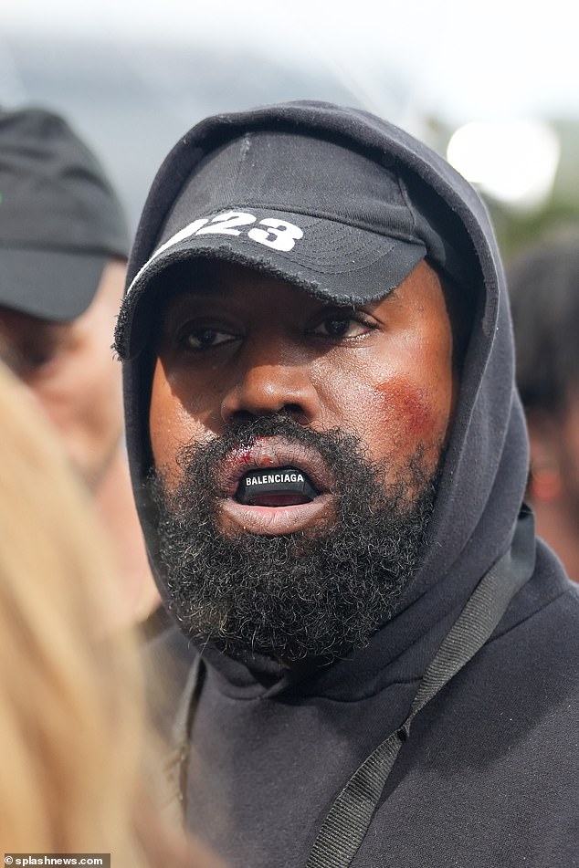 Declaración: Kanye West, de 45 años, salió con misteriosas marcas rojas en la cara y un protector bucal de Balenciaga cuando llegó al desfile de Givenchy durante la Semana de la Moda de París.