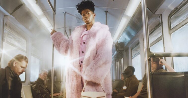 Lil Nas X combina un abrigo de piel de oveja morado con un bolso color canela para Coach